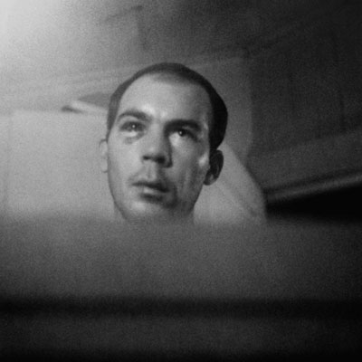 A black and white photo of a young man, beaten up.