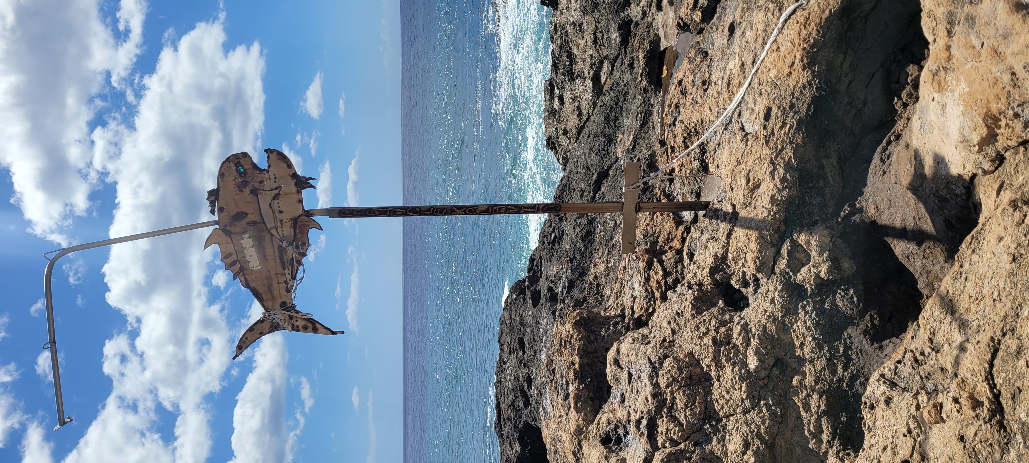 A metal pole sticking out of coral rock, with an angler fish at the end.