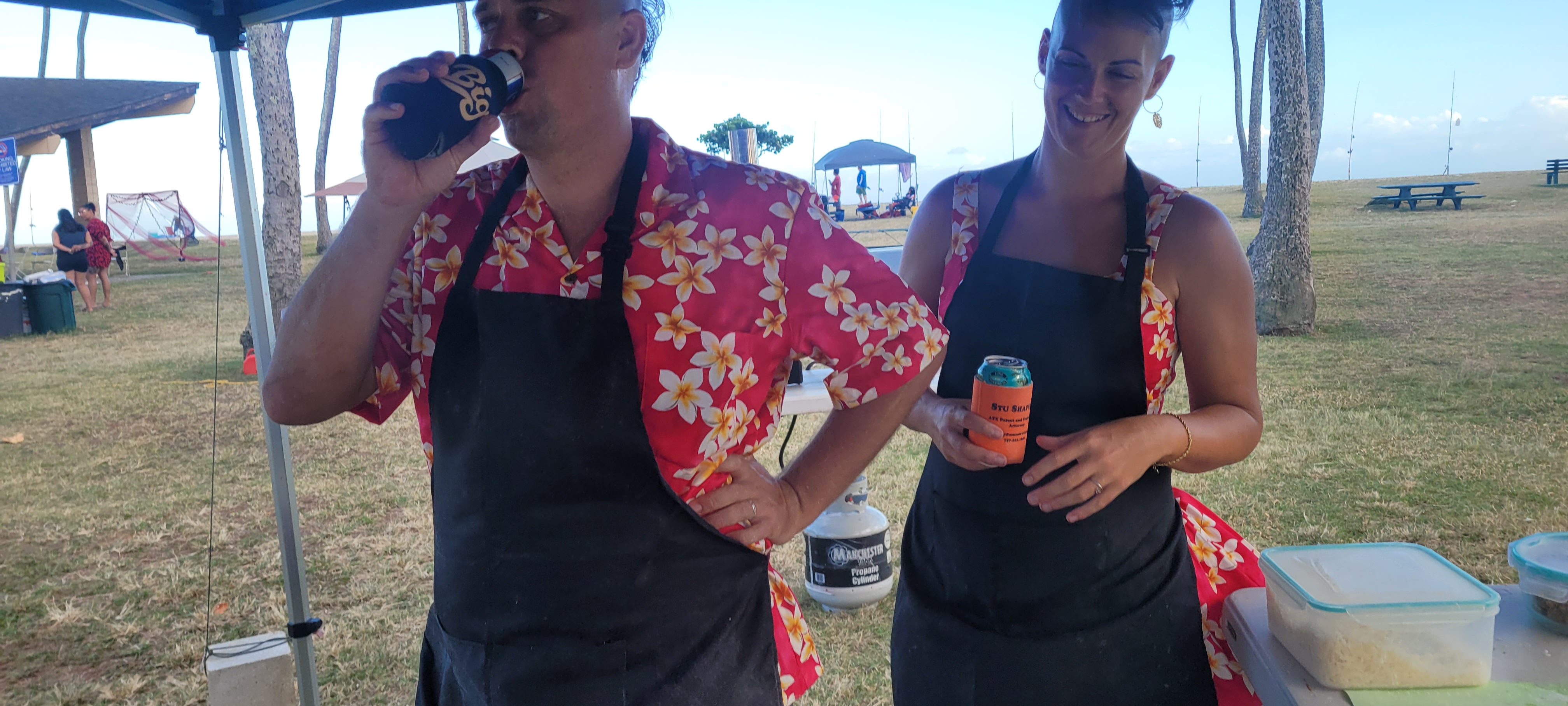 A couple in red aloha shirts and black aprons.