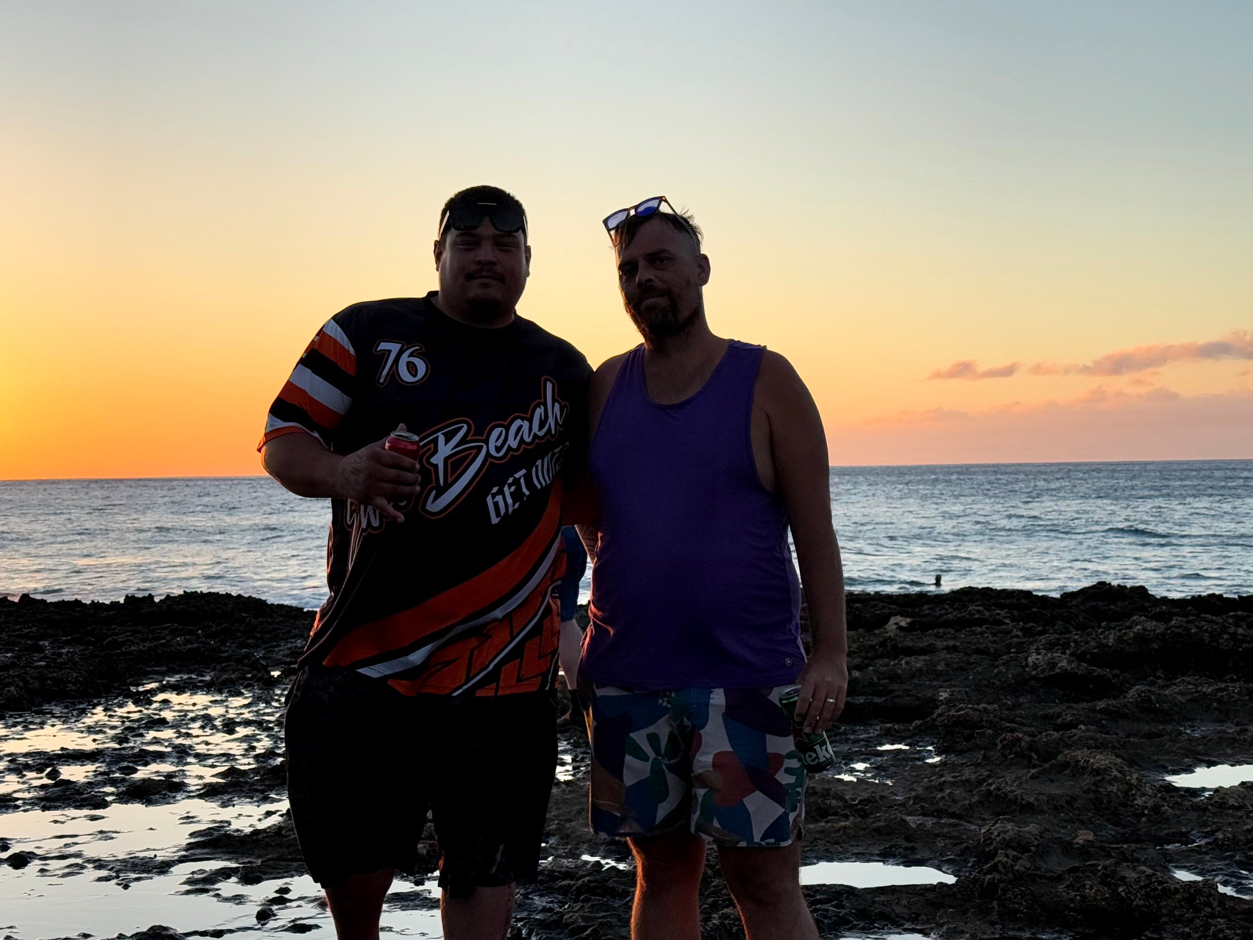 Two men standing with the sunset behind them.