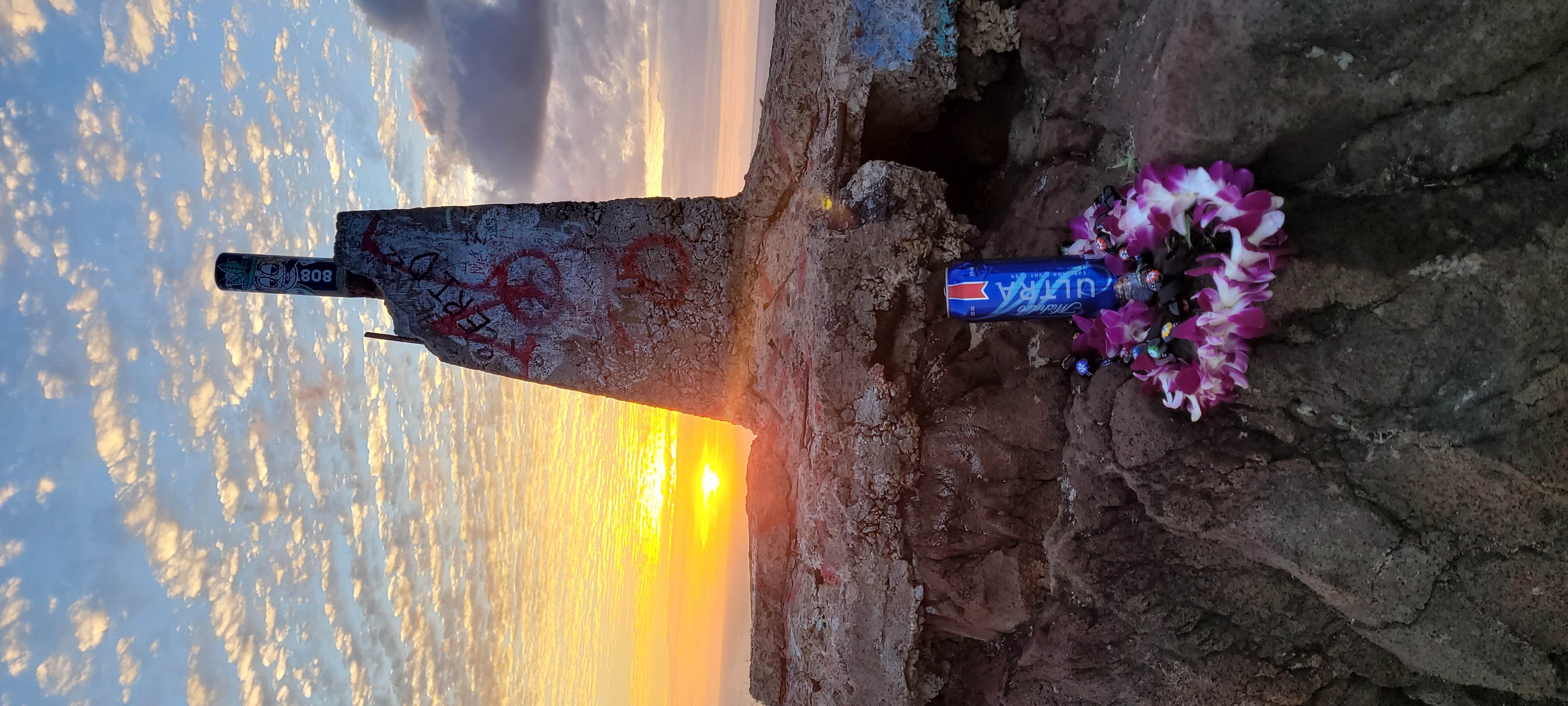 A sunset, and an informal shrine, at the top of a mountain.
